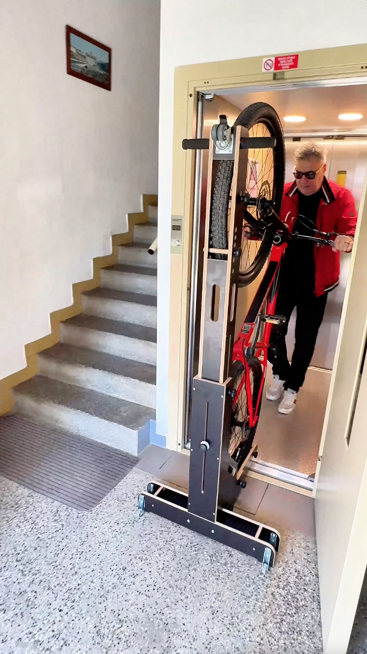 Muž v červené bundě zajíždí s kolem ve stojanu BIKERECT do výtahu.